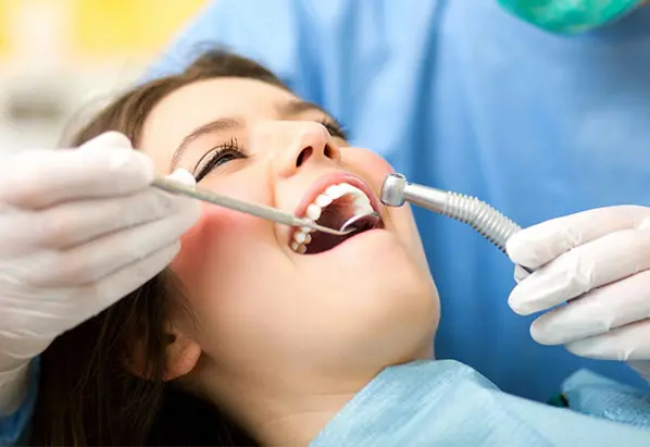 Senior dentist curing a female patient